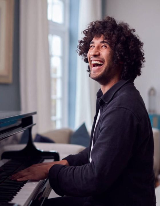 young-man-sitting-at-grand-piano-and-playing-at-ho-2021-08-30-06-14-52-utc-e1697687758956.jpg